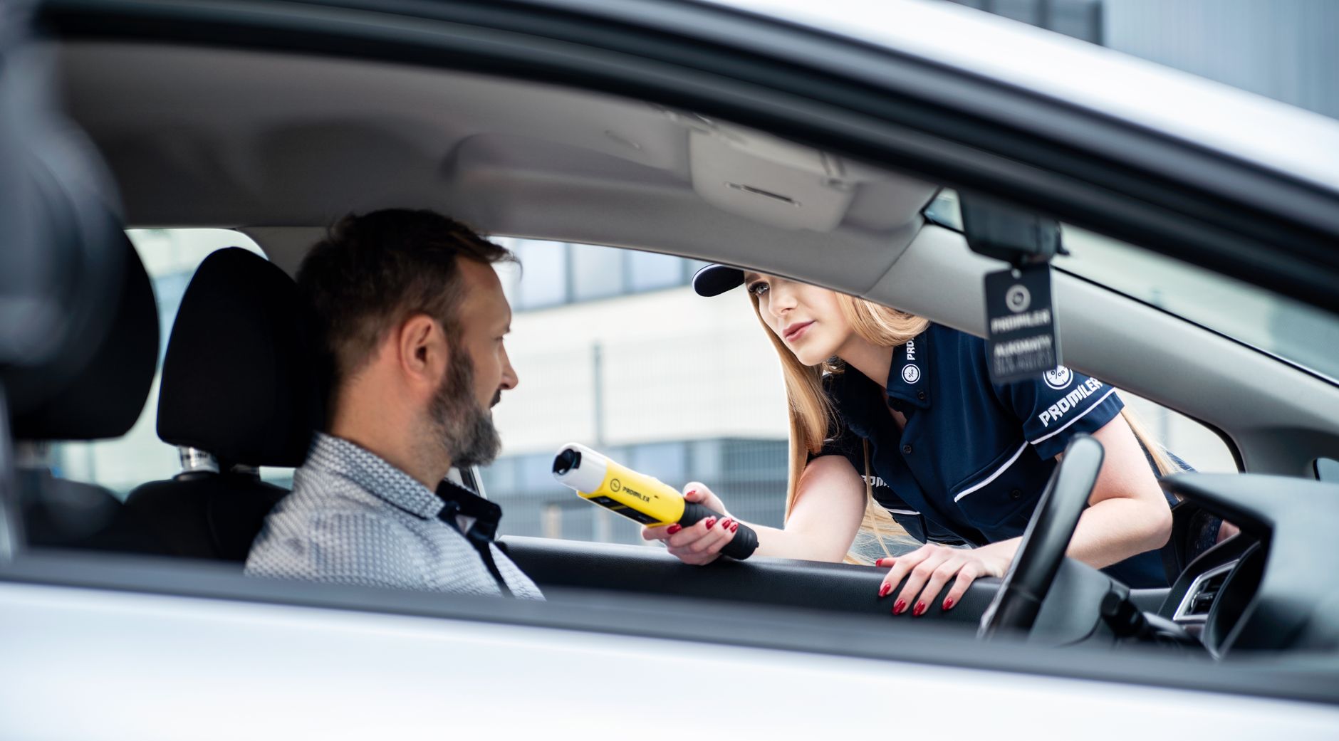A police officer conducts a breathalyzer test on a male driver during a road safety check.