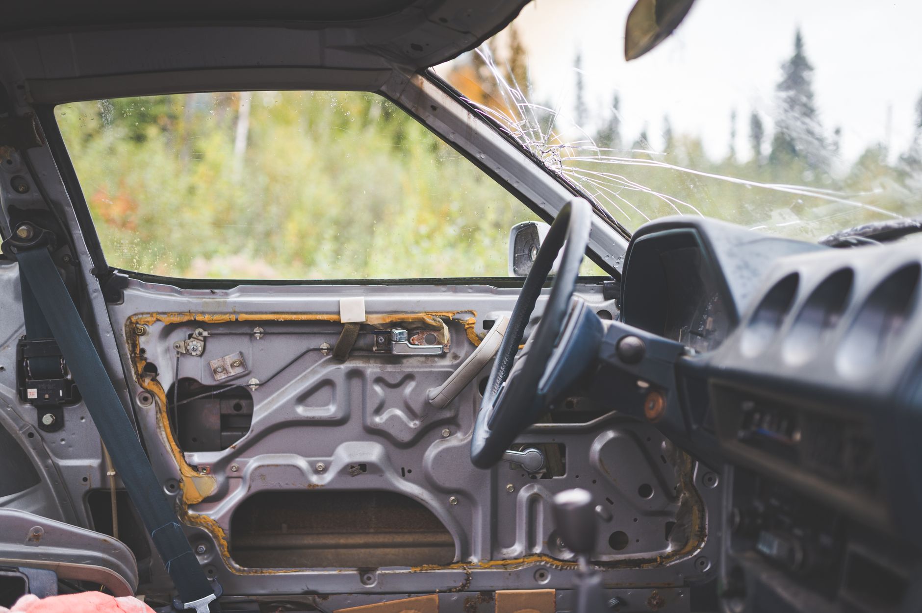 Explore the neglected interior of an abandoned car, showcasing broken windows and rustic details.