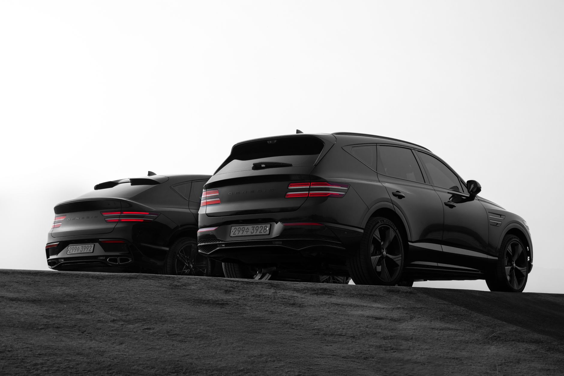 Sleek black Genesis GV80 SUVs parked on a hill. Minimalist and luxurious automotive design.