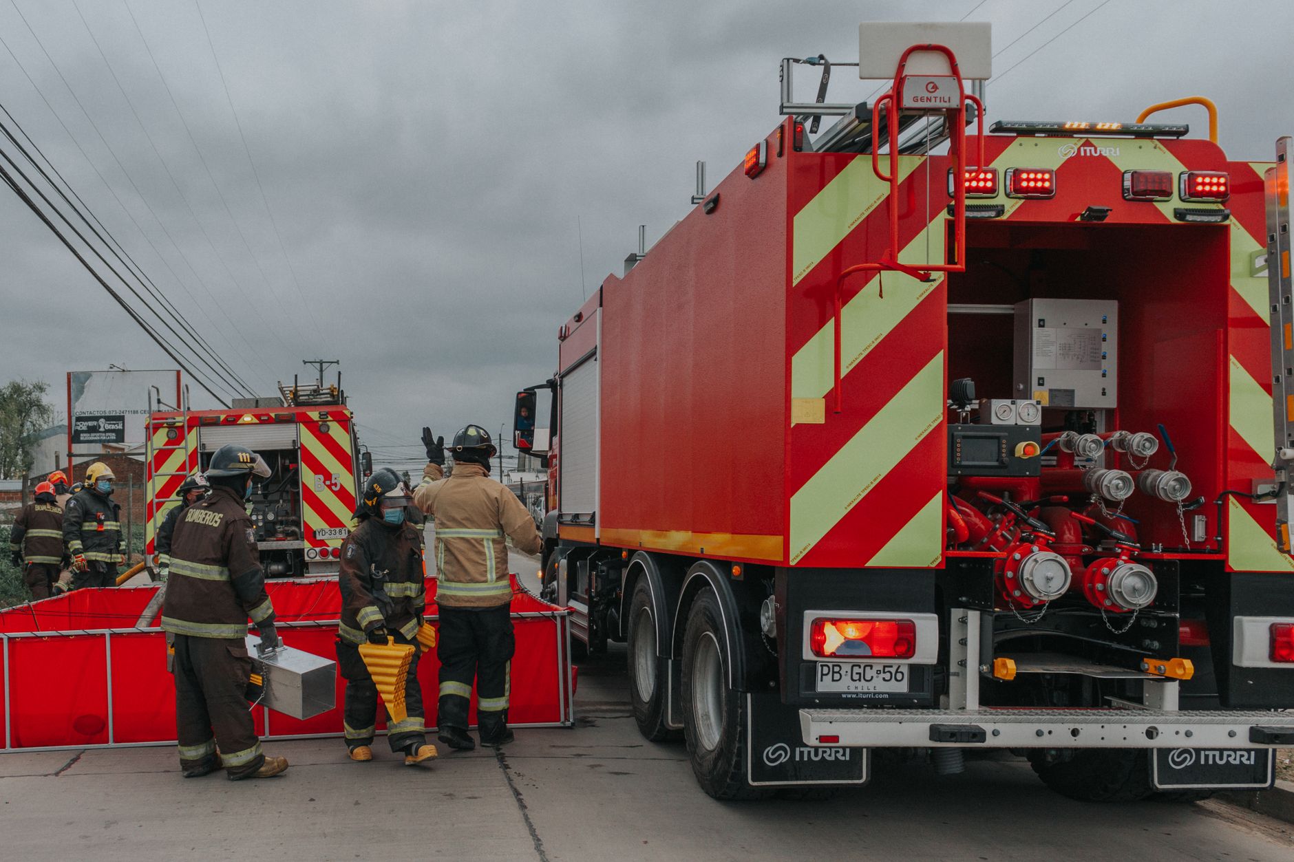Firefighters preparing equipment with fire trucks during an emergency response effort.