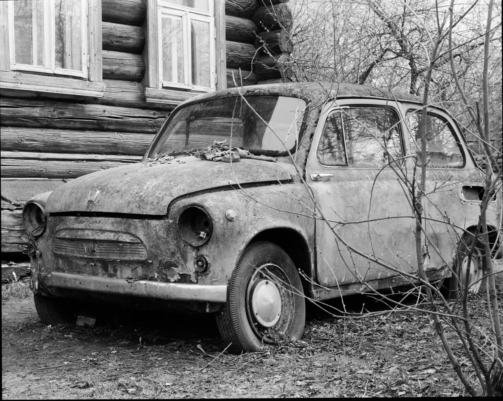 Rustic scene featuring an abandoned ZAZ 965 near a wooden house.