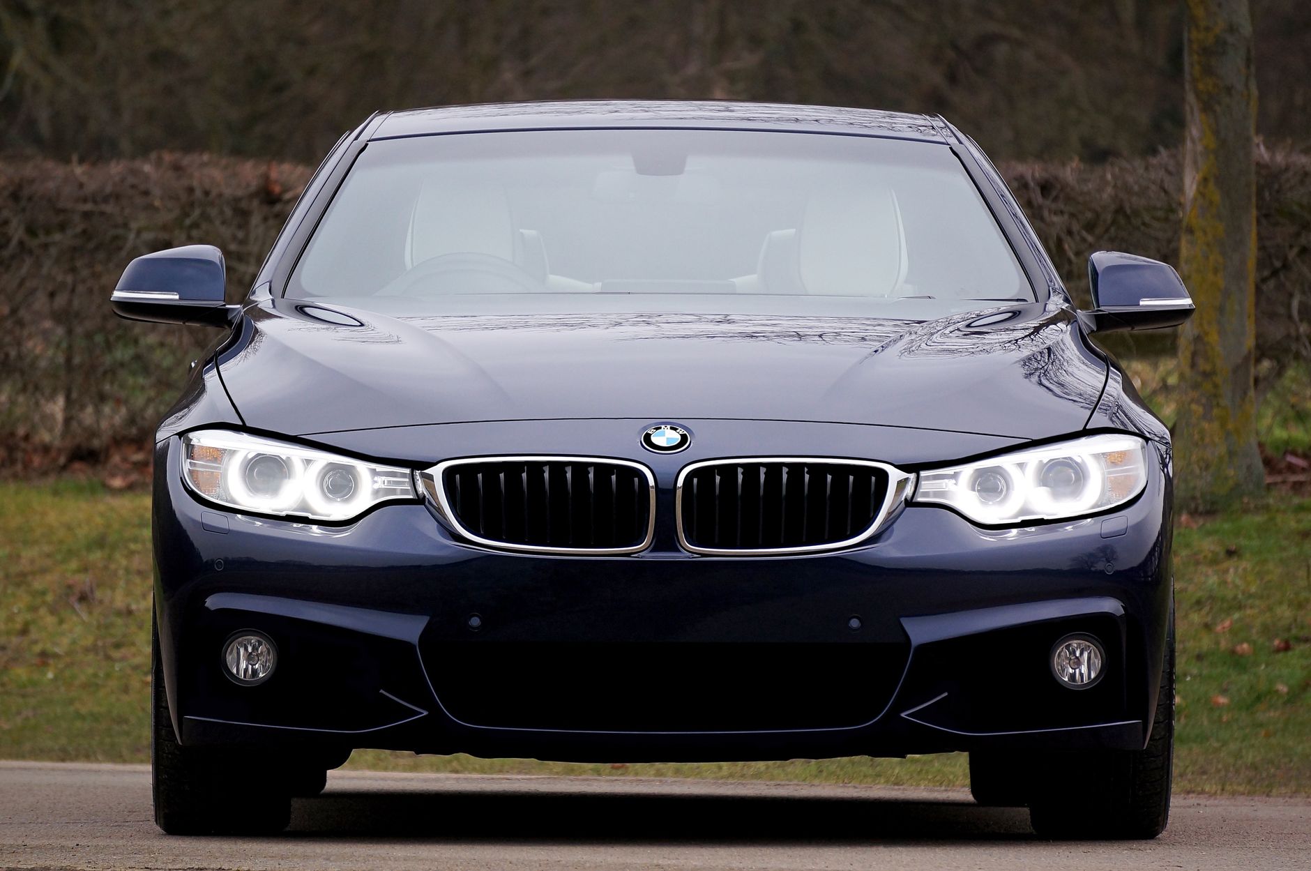 A sleek, blue luxury sedan car with illuminated headlights, emphasizing elegance and modern design.