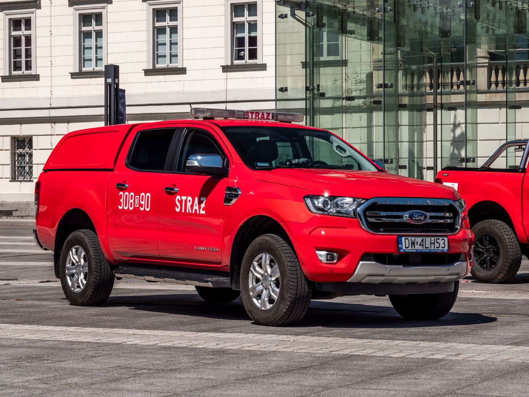A vibrant red fire brigade truck parked in a European city setting during the day.