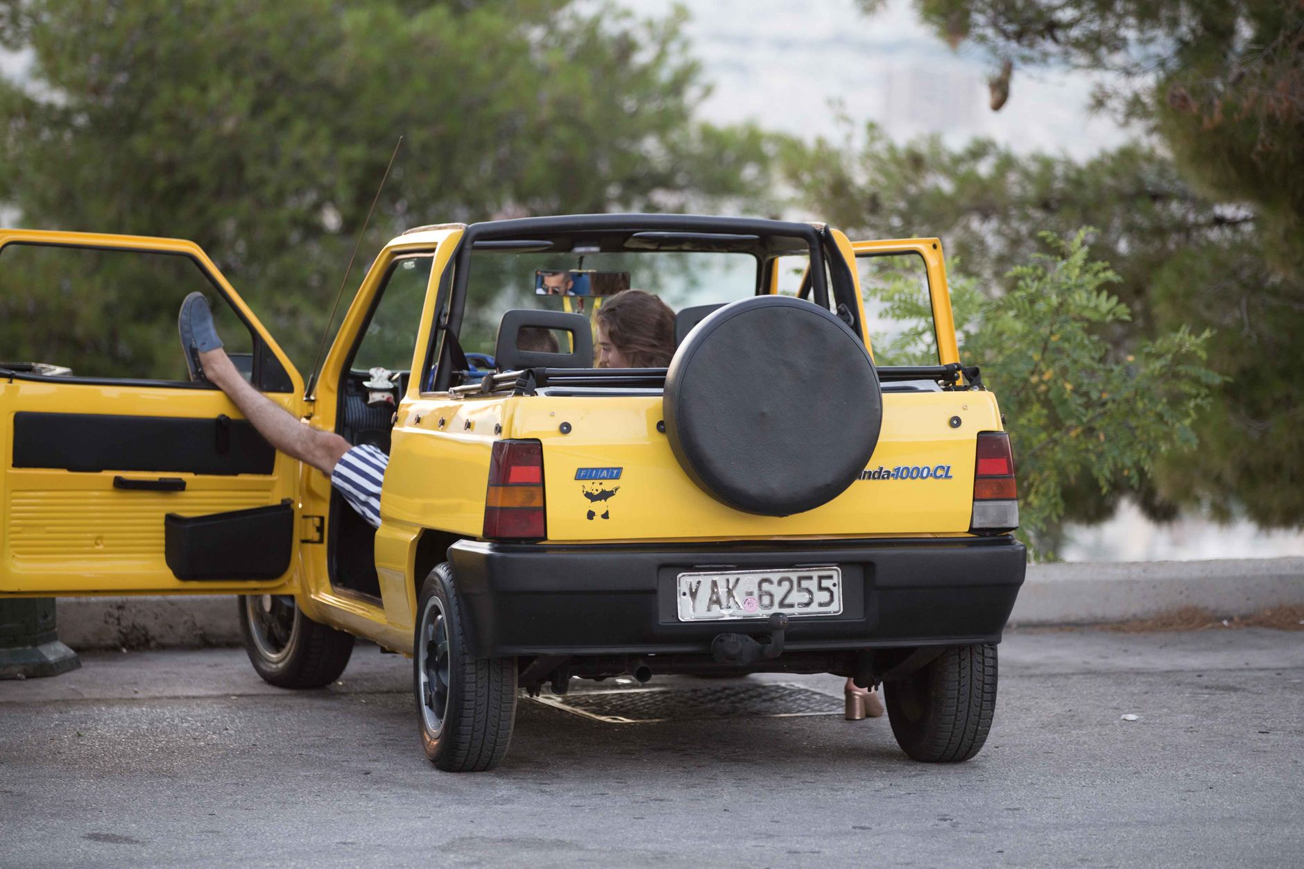 Relaxed scene featuring a vintage Fiat Panda with open doors in a scenic outdoor setting.