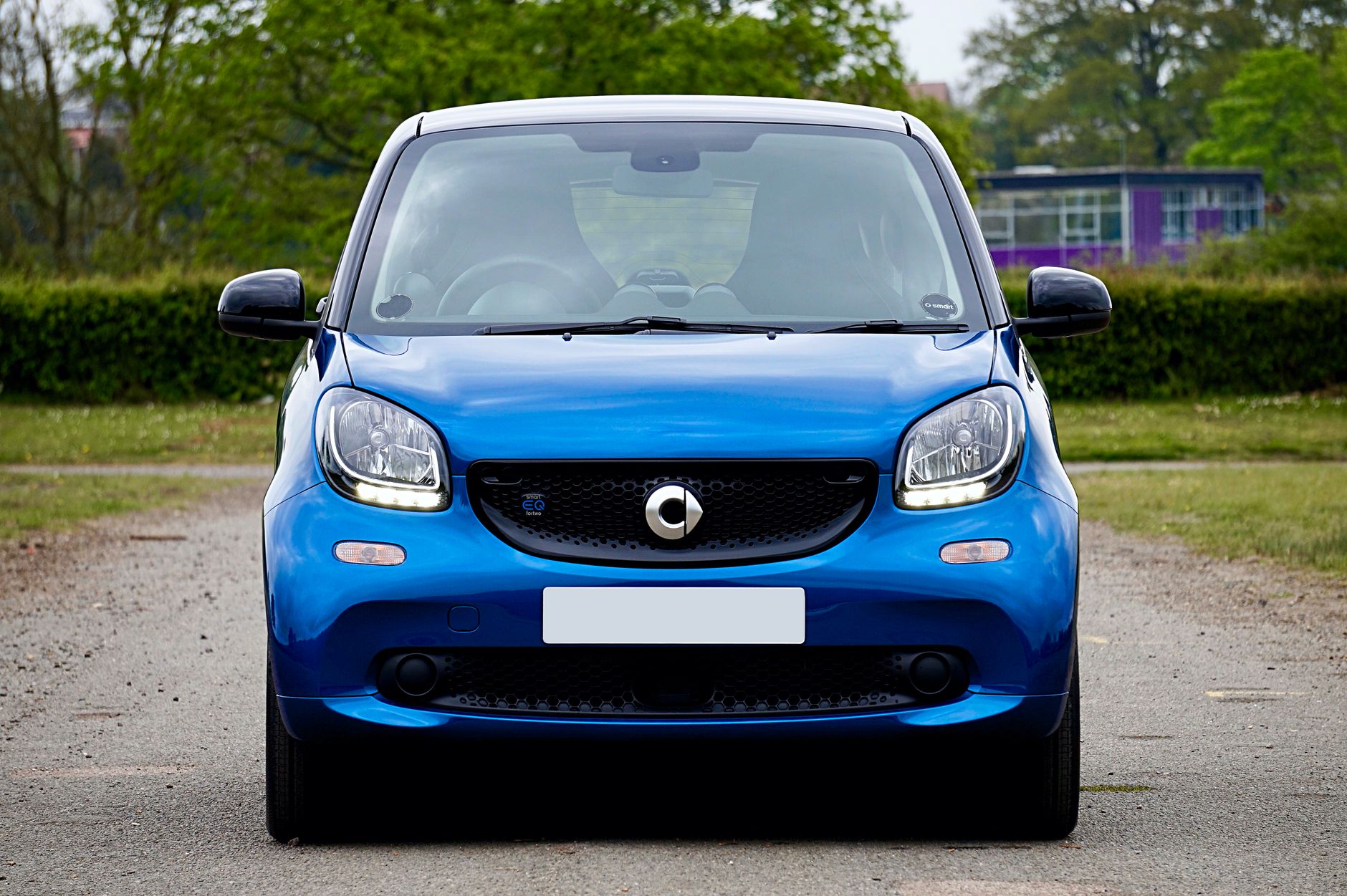 Blue electric smart car parked on an outdoor road in the UK.