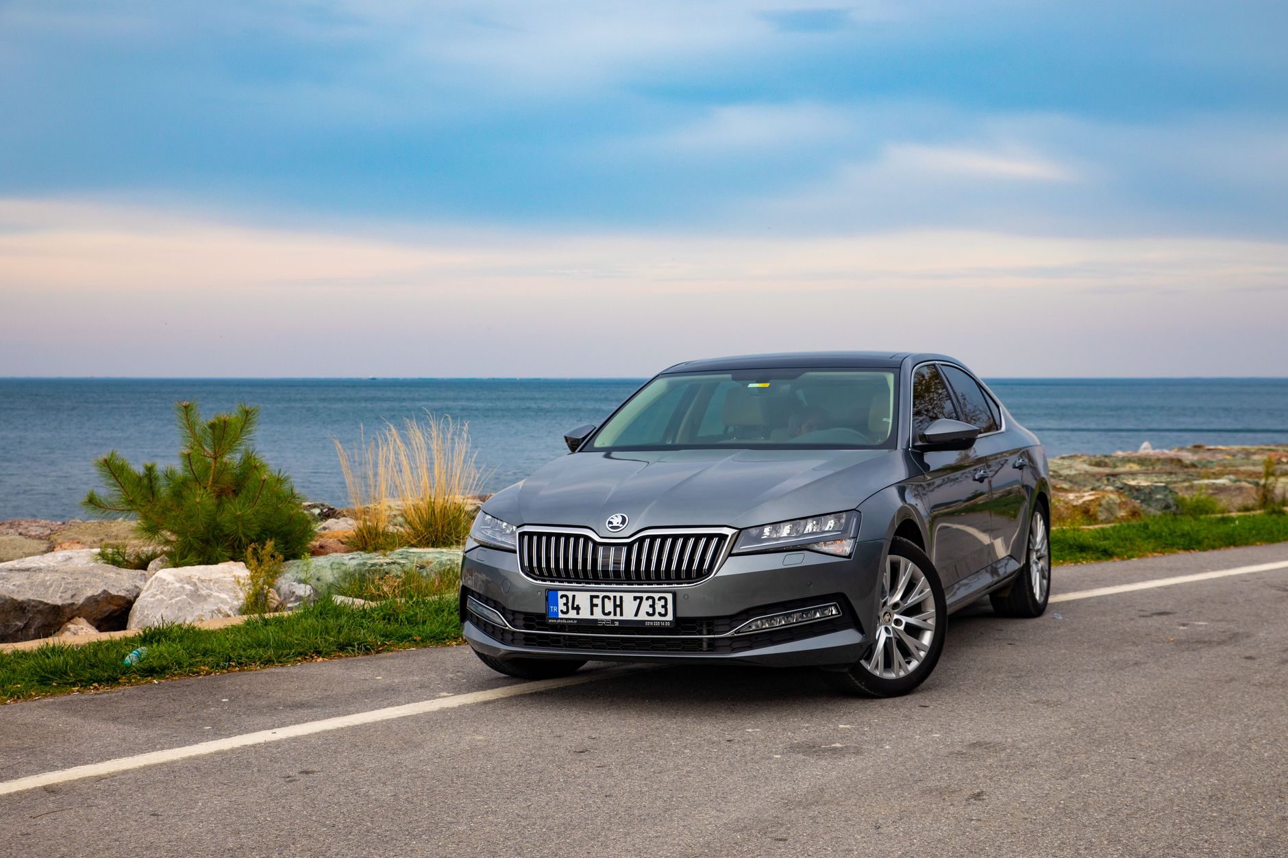 A sleek grey Skoda Superb sedan parked by a scenic seaside in Sinop, Türkiye.