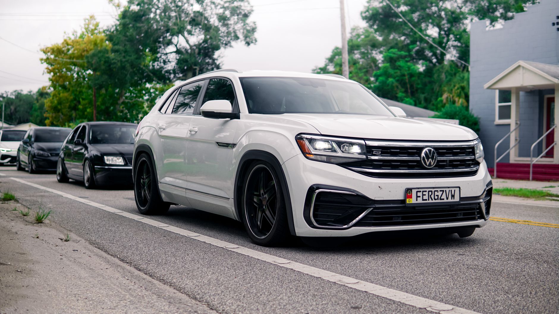 White Volkswagen Atlas Cross Sport on a city street, showcasing urban transportation.