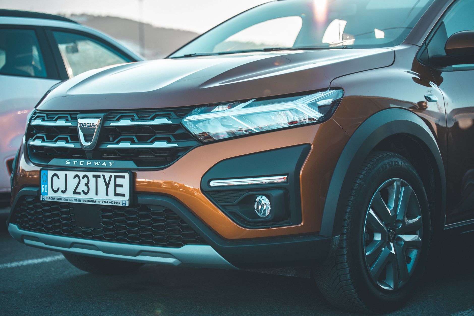 Close-up of a brown Dacia Stepway car showcasing its front grille and headlights.