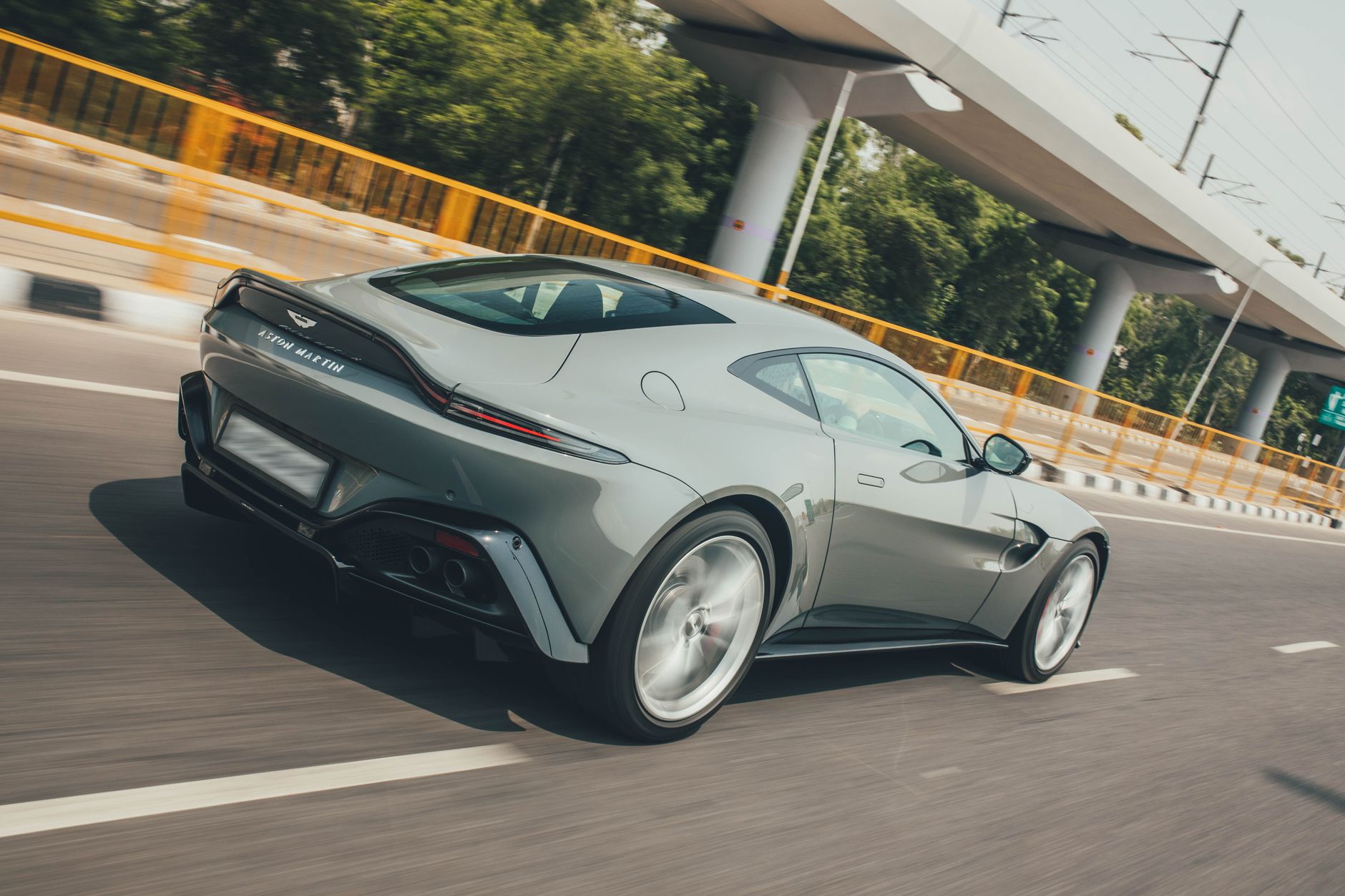 Sleek Aston Martin Vantage zooming on a highway in New Delhi, India.