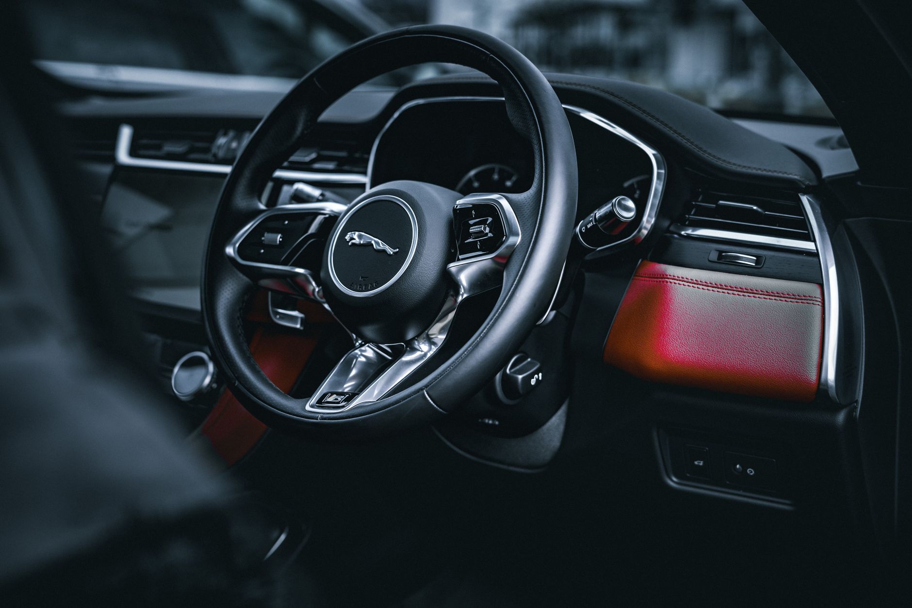 Close-up of a luxury Jaguar car interior with a sleek steering wheel and modern design.