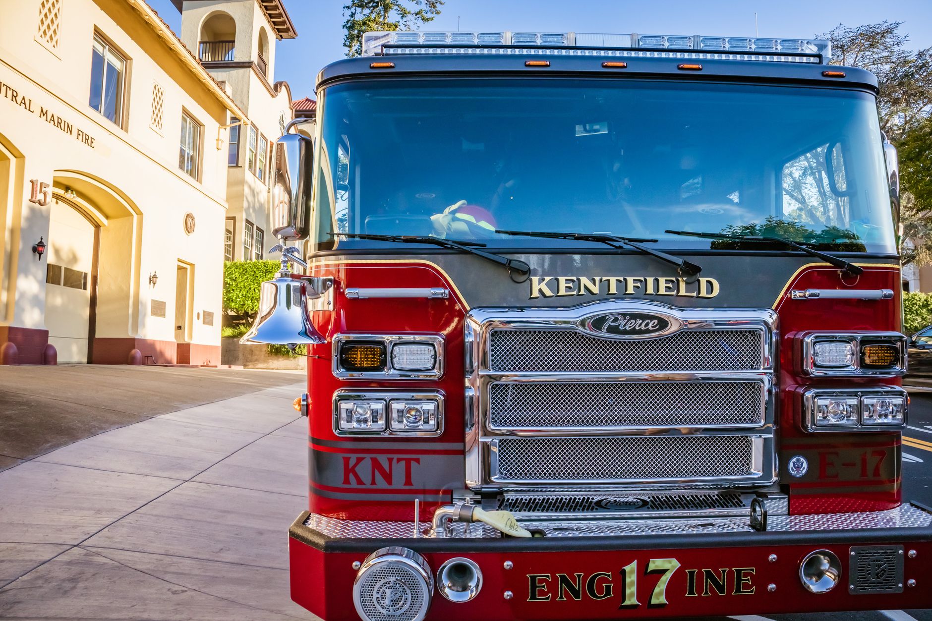 Front view of a red fire truck parked in front of Central Marin Fire Station on a sunny day.