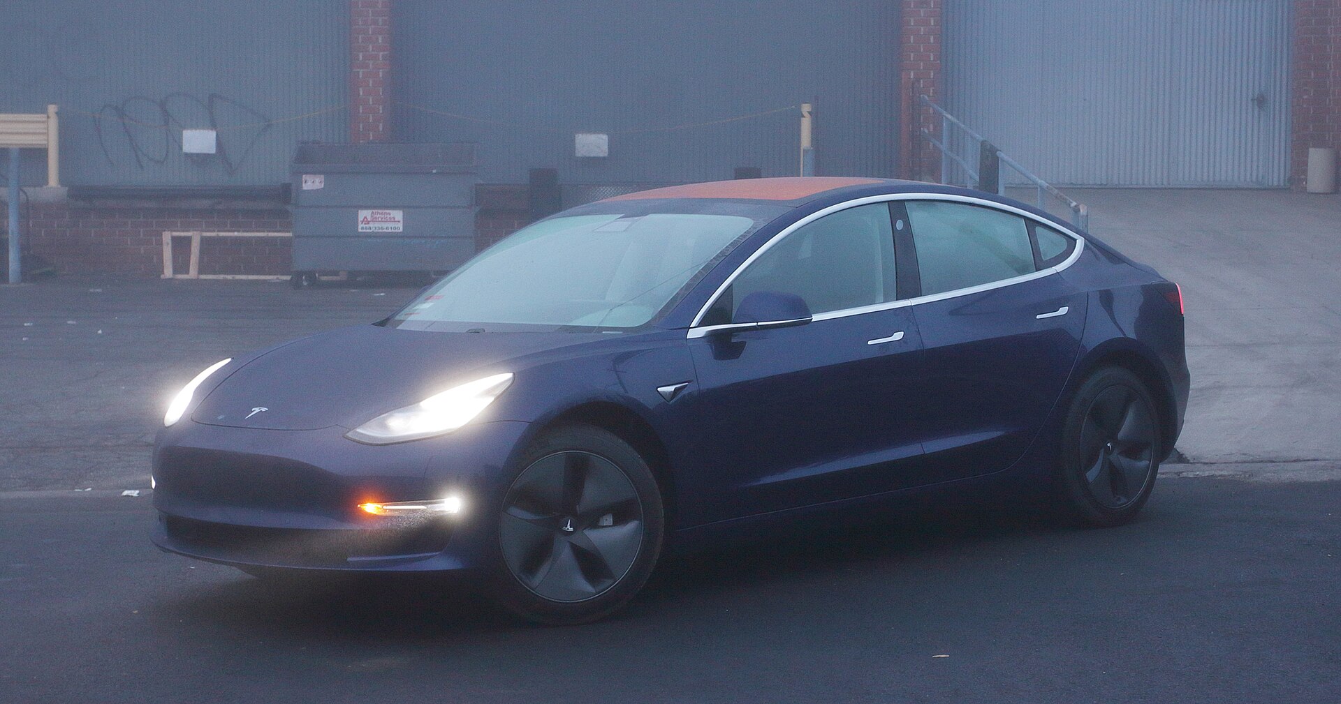 blue 2018 tesla model 3 long range against industrial building