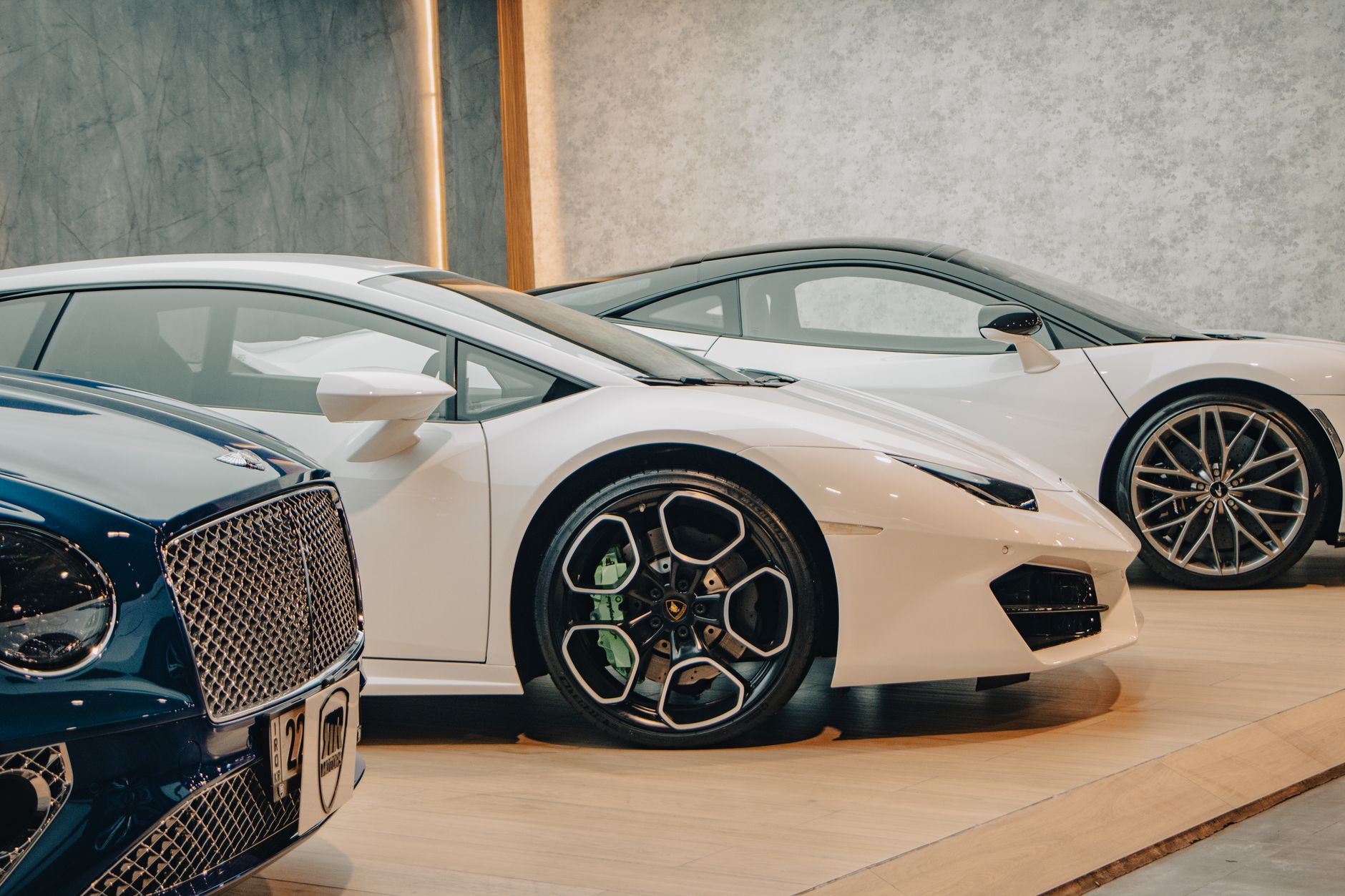 A lineup of sleek luxury sports cars on display in an upscale showroom setting.