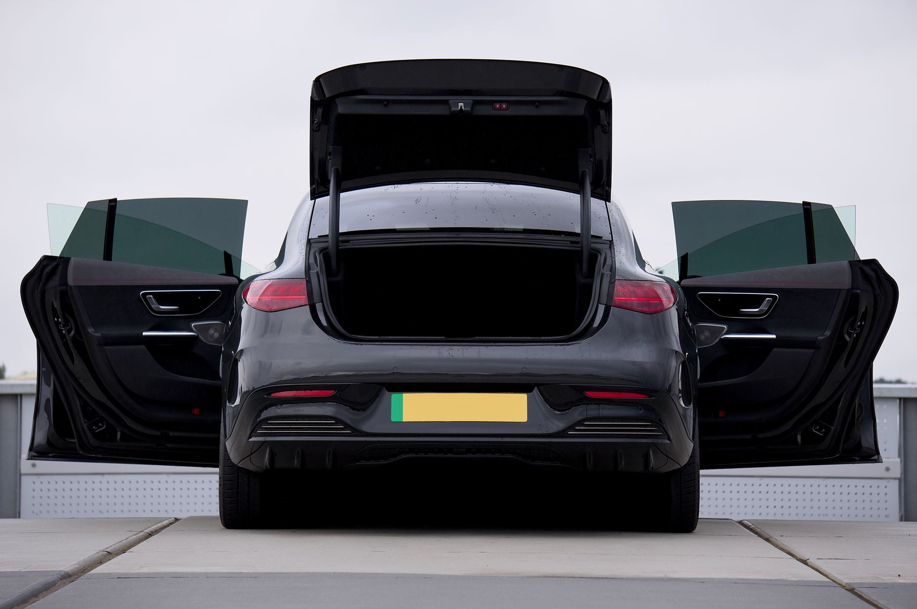 Sleek black electric car with open doors and trunk, showcasing modern design and luxury.