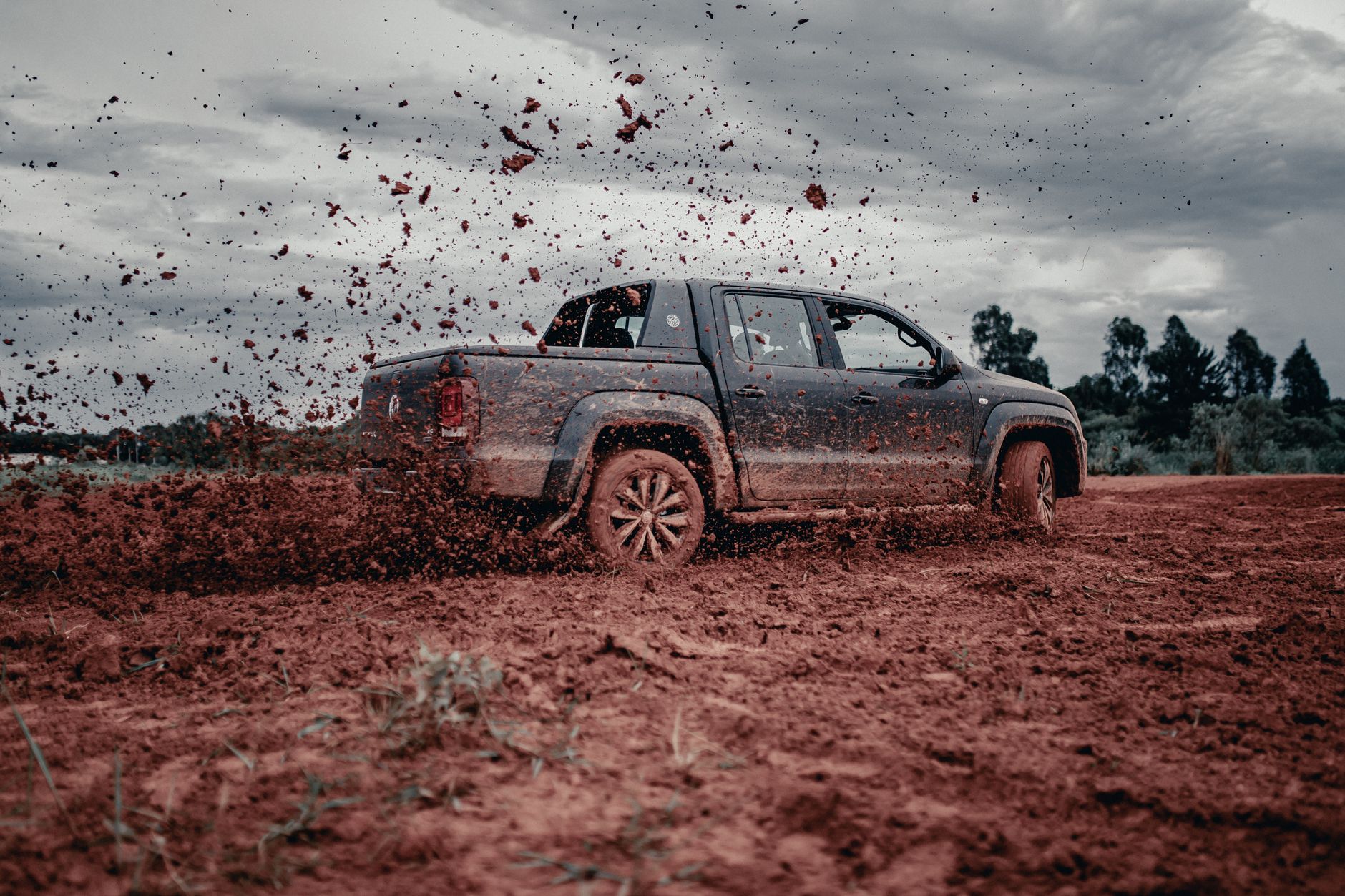 A pickup truck splashes through muddy terrain, capturing the thrill of off-road driving.