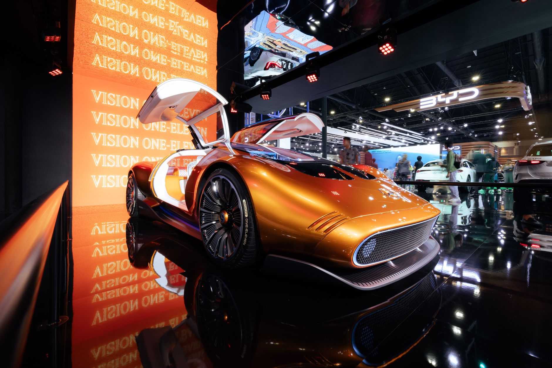 A sleek futuristic concept car in vivid orange displayed at an international motor show.