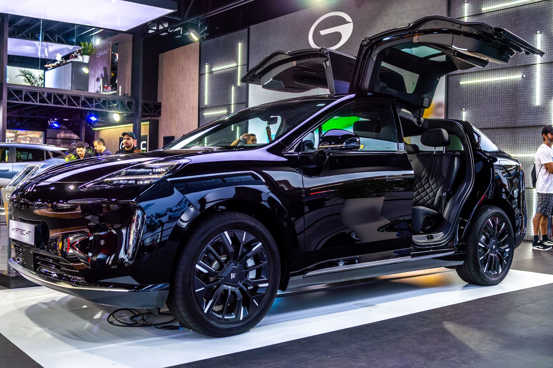 Sleek black electric SUV displayed with gullwing doors at São Paulo auto show, showcasing modern technology.
