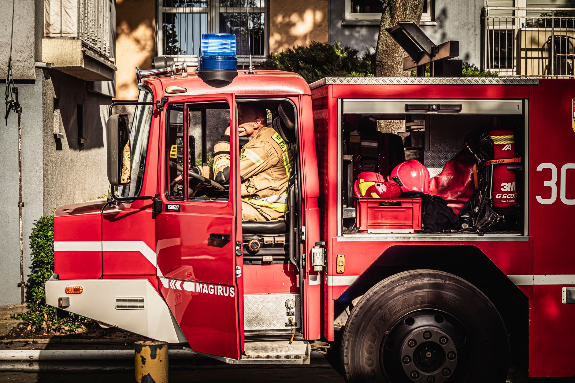 Firefighters ready in a fire truck in Wrocław, Poland, on a sunny day.