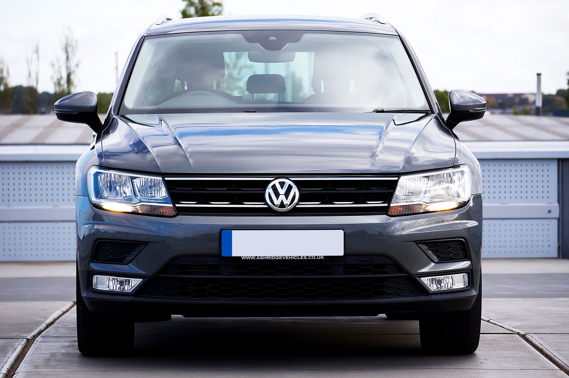 A stylish gray Volkswagen Tiguan photographed head-on in a modern urban setting. Ideal for automotive themes.
