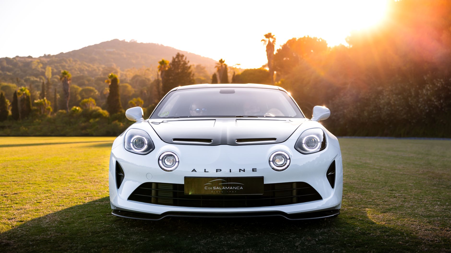 Front view of a white Alpine sports car in a scenic location with sunset.