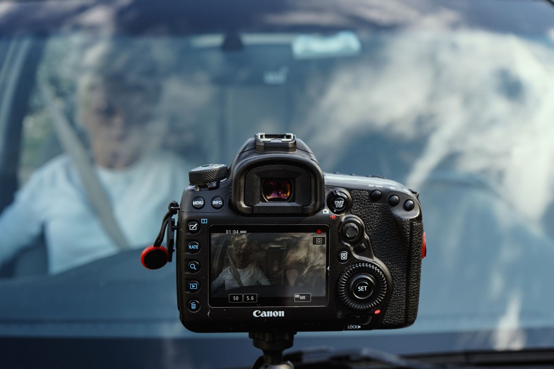Close-up of a video camera rig mounted in front of a car with reflection of clouds.