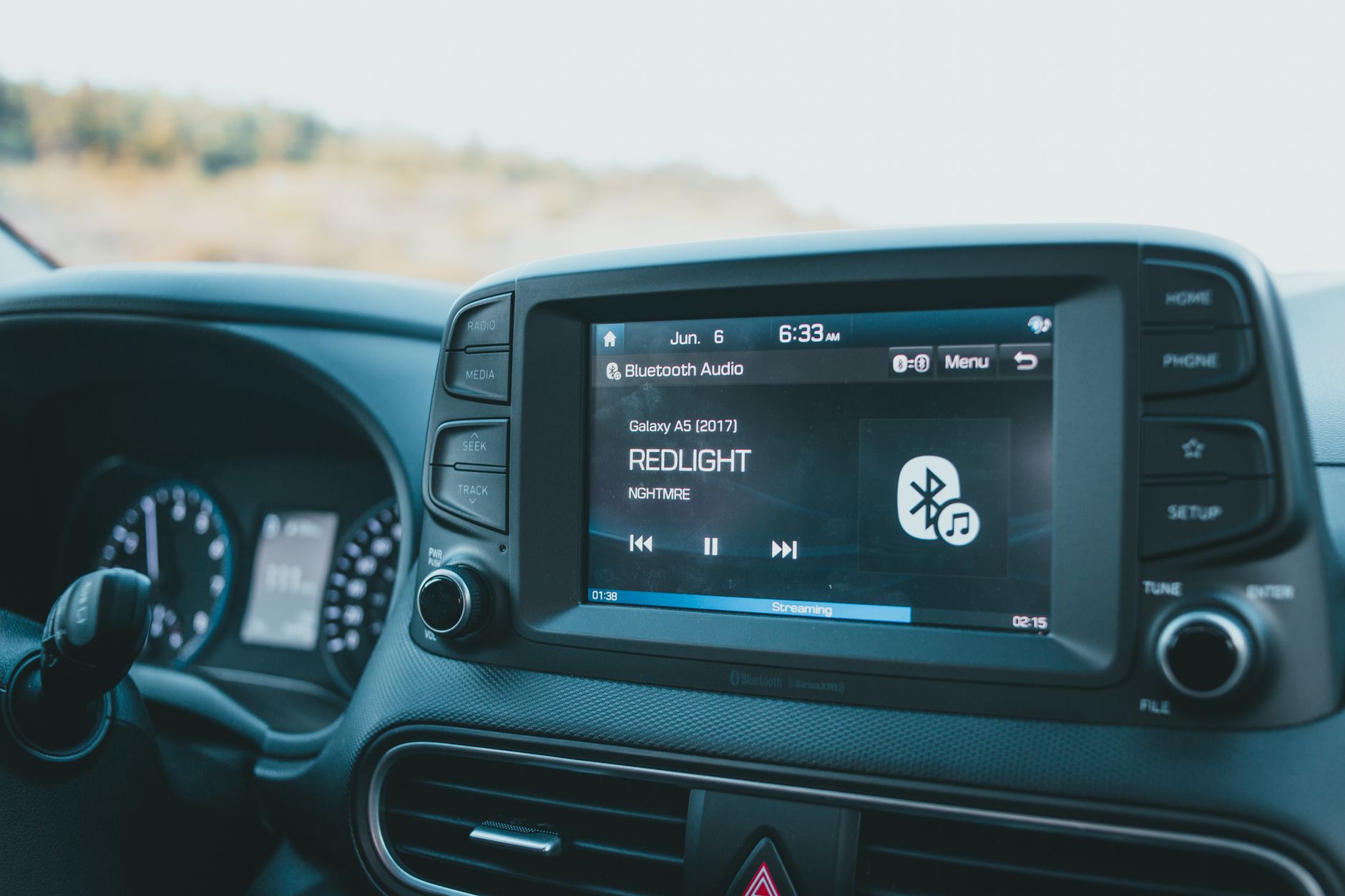 Close-up of a car dashboard featuring a Bluetooth audio system with music display.