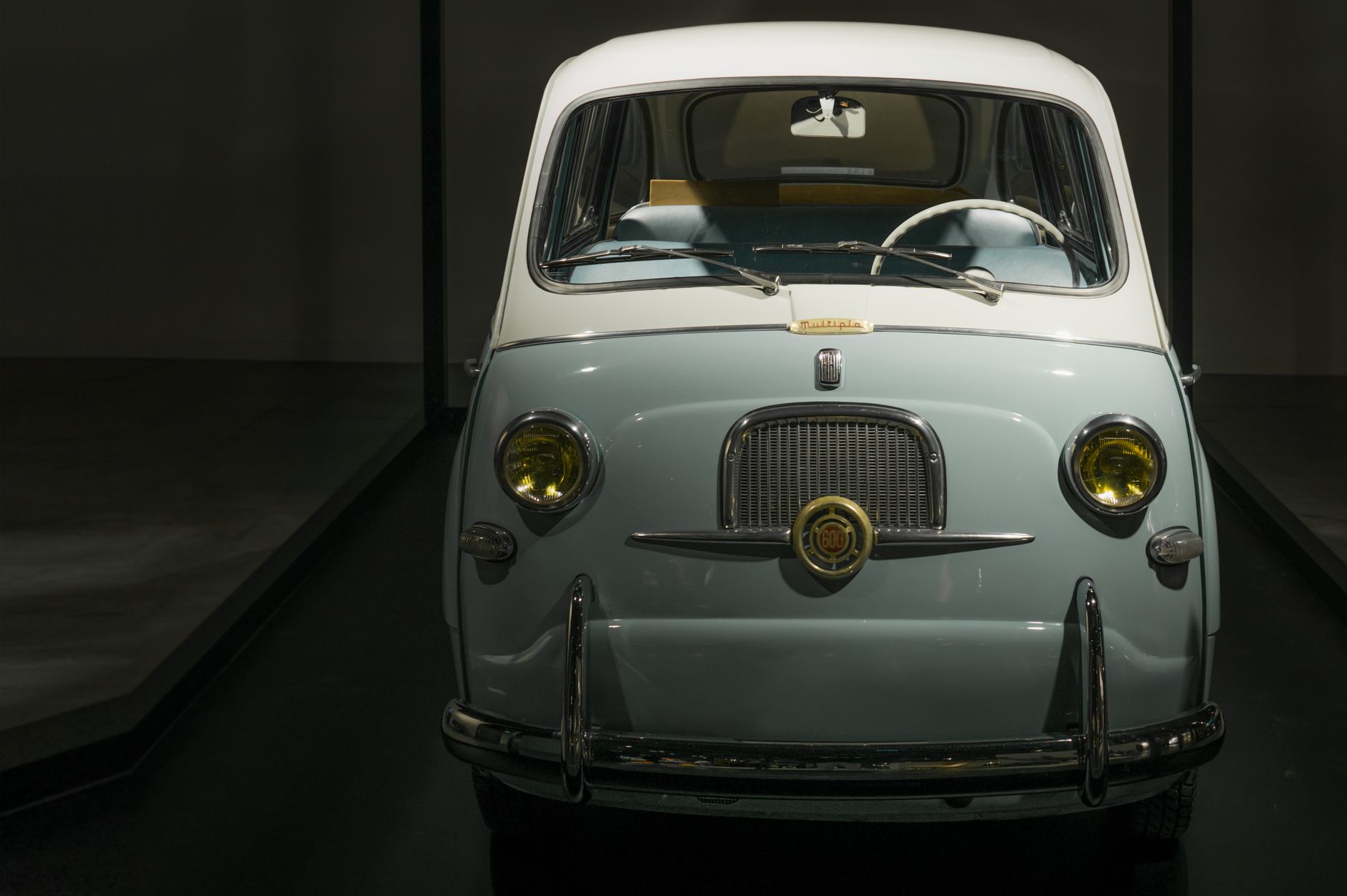 Classic Fiat 600 Multipla displayed indoors with shiny chrome details and vintage design.