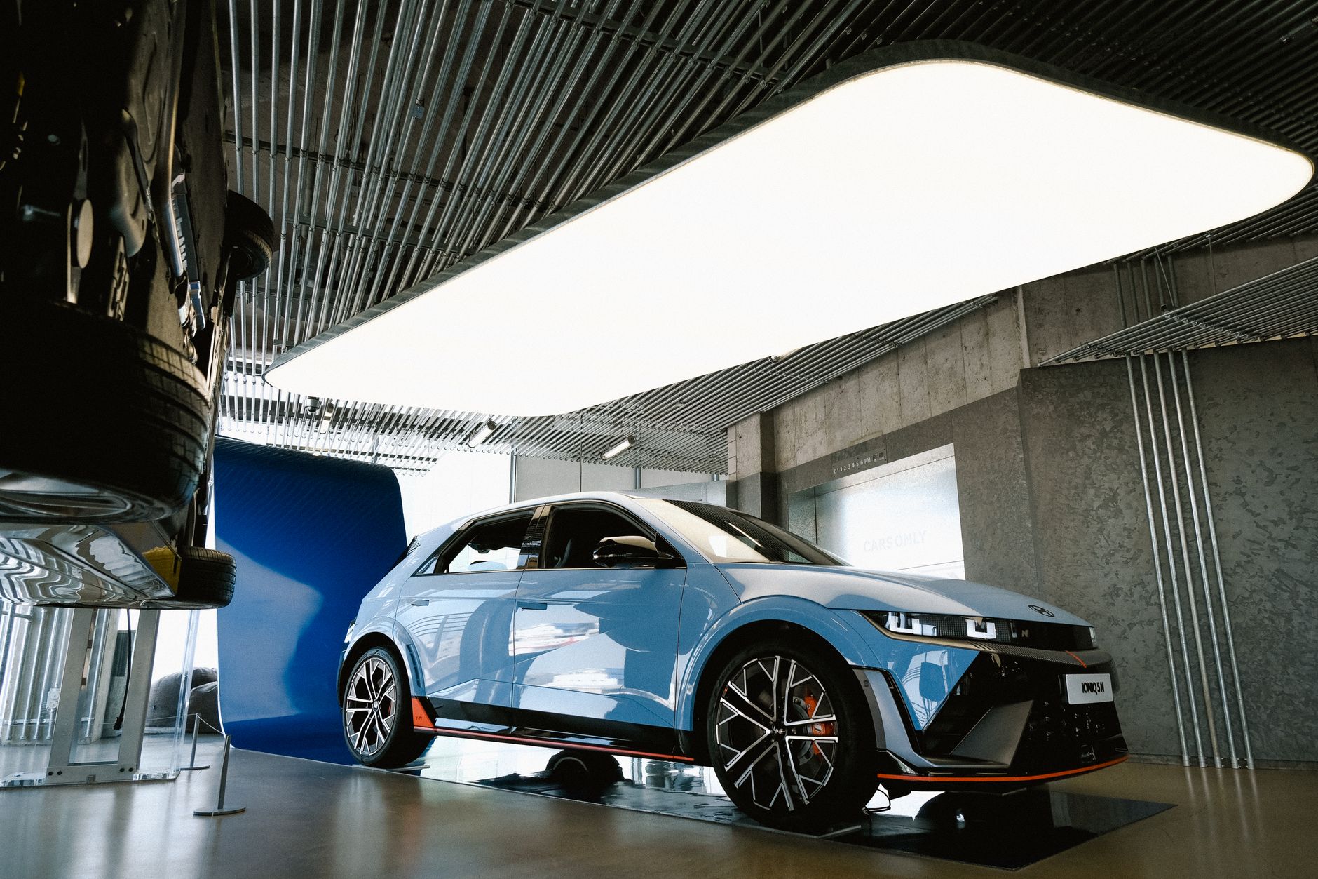 Sleek blue electric car showcased indoors with modern lighting and design.