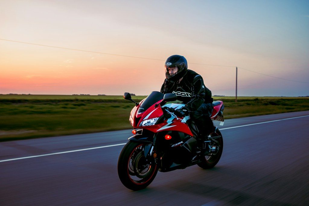 Motocyklista w trakcie jazdy, po drodze między polami