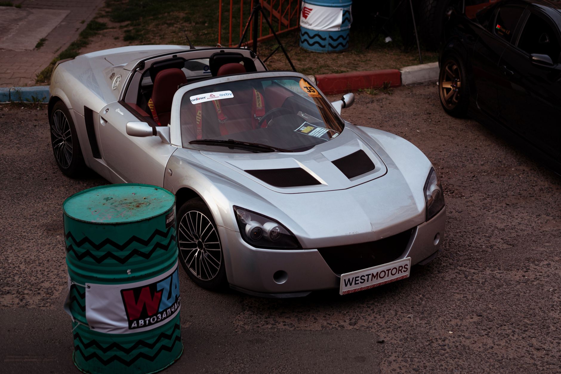 A sleek silver convertible car displayed at an outdoor car show, featuring a modern design and stylish elements.
