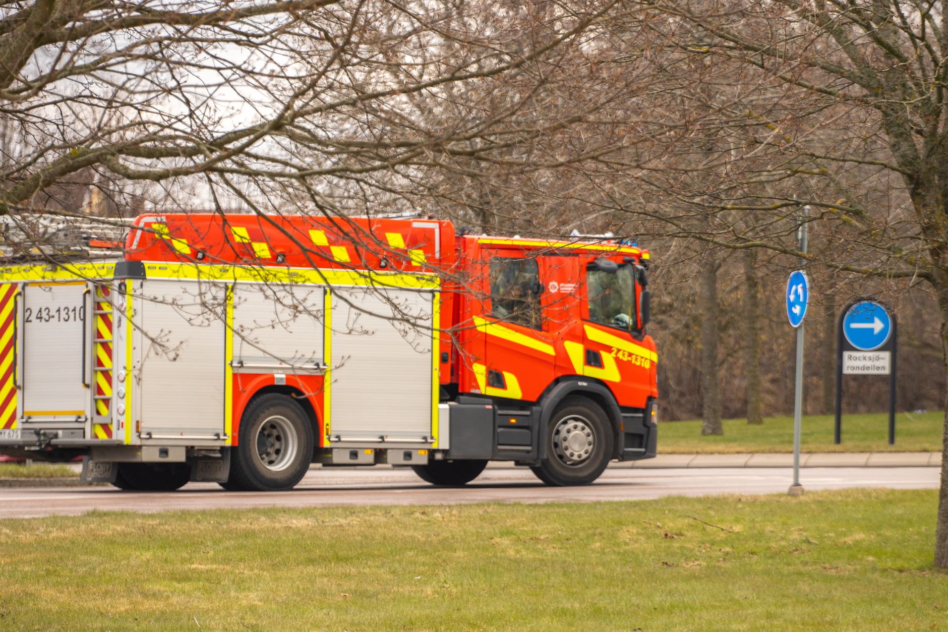 A vibrant red fire truck navigating a suburban street in Jonkoping, Sweden.