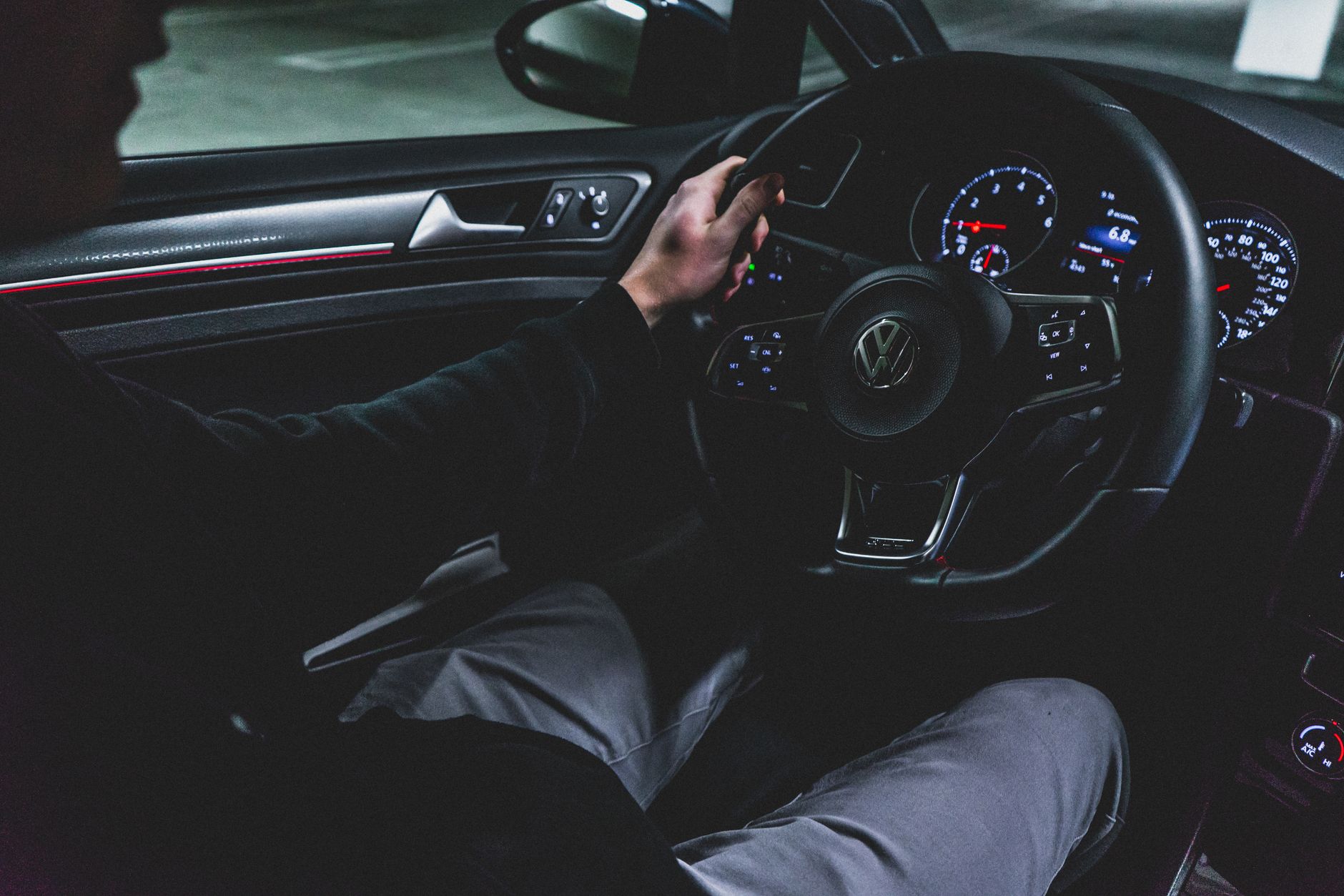 Interior view of a person driving a modern Volkswagen car at night, showing dashboard and steering wheel.
