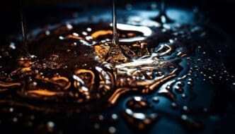 Makrofotografia lejącego się oleju na ciemnym tle z refleksami światła i detalami kropli.
