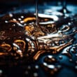 Makrofotografia lejącego się oleju na ciemnym tle z refleksami światła i detalami kropli.